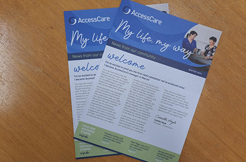 Two printed copies of the AccessCare newsletter on a desk